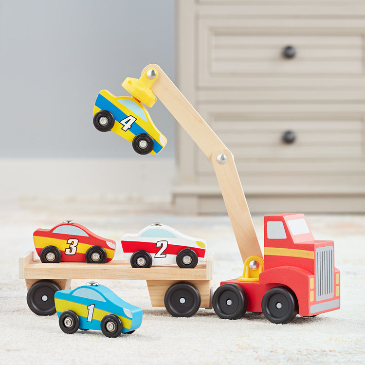 A playroom scene with The Melissa & Doug Magnetic Car Loader Wooden Toy Set With 4 Cars and 1 Semi-Trailer Truck