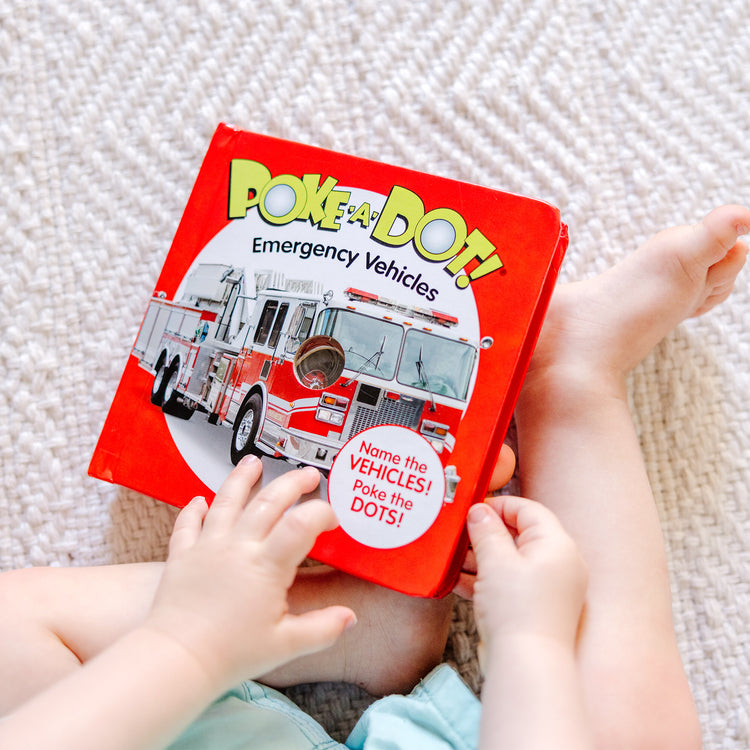 A kid playing with The Melissa & Doug Children’s Book – Poke-a-Dot: Emergency Vehicles (Board Book with Buttons to Pop)