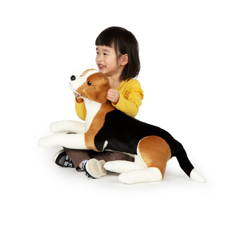 A child on white background with The Melissa & Doug Lifelike Plush Beagle Stuffed Animal