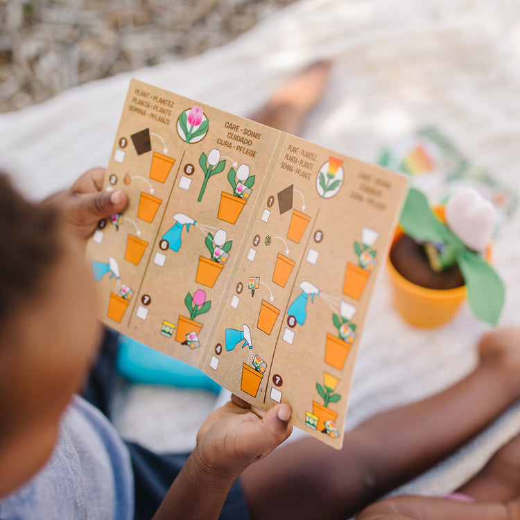 A kid playing with The Melissa & Doug Let’s Explore Flower Gardening Play Set with Color-Changing Flowers (16 Pieces)