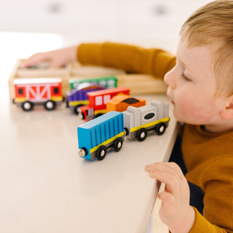 A kid playing with The Melissa & Doug Wooden Magnetic Train Cars - 8 Piece Educational and Skill-Building Wooden Toy for Boys and Girls