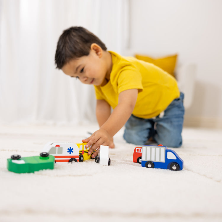 A kid playing with The Melissa & Doug Wooden Town Vehicles Set in Wooden Tray (9 pcs)