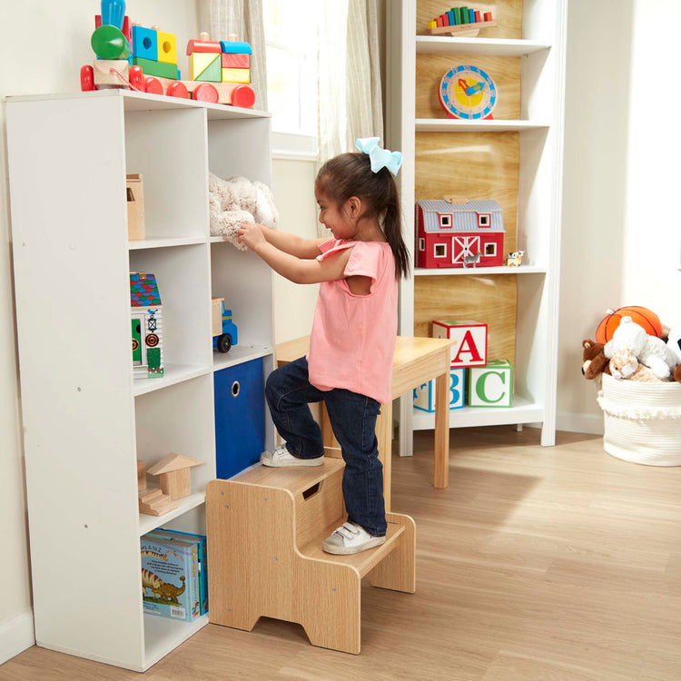 A kid playing with The Melissa & Doug Kids Wooden Step Stool - Light Natural Finish