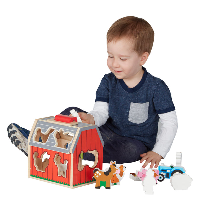 A child on white background with The Melissa & Doug Wooden Take-Along Sorting Barn Toy with Flip-Up Roof and Handle 10 Wooden Farm Play Pieces