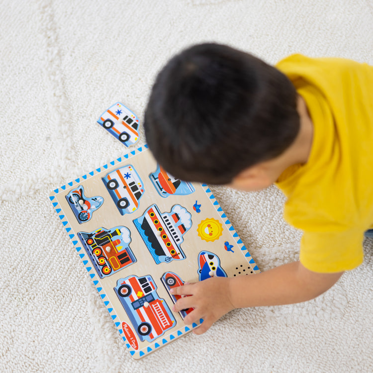 A kid playing with The Melissa & Doug Vehicles Sound Puzzle - Wooden Peg Puzzle With Light-Activated Sound Effects (8 pcs)