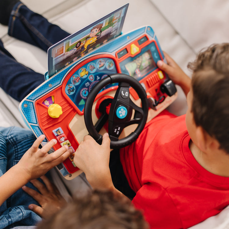 A kid playing with The Melissa & Doug PAW Patrol Rescue Mission Wooden Dashboard