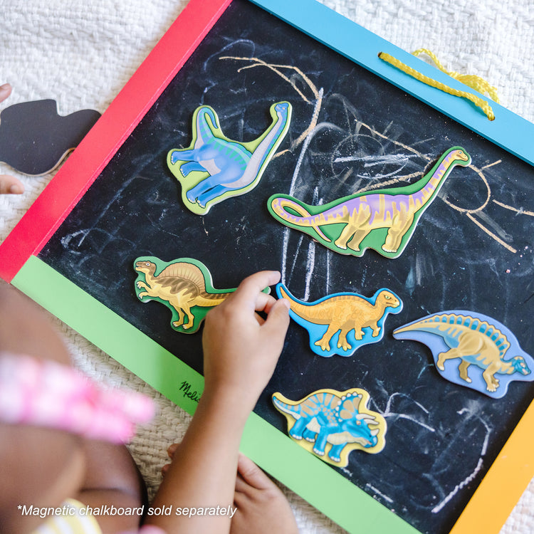 A kid playing with The Melissa & Doug Magnetic Wooden Dinosaurs in a Wooden Storage Box (20 pcs)