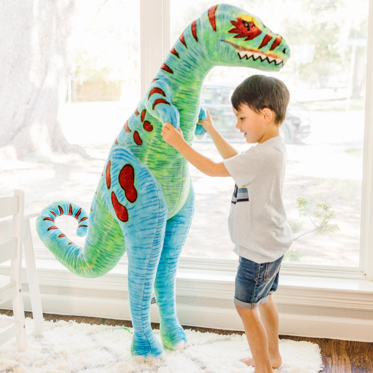 A kid playing with The Melissa & Doug Standing T-Rex Giant Lifelike Plush Stuffed Animal