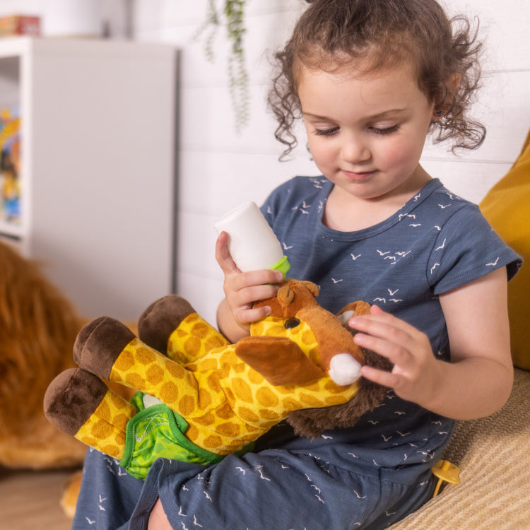 A kid playing with The Melissa & Doug 11-Inch Baby Giraffe Plush Stuffed Animal with Pacifier, Diaper, Baby Bottle