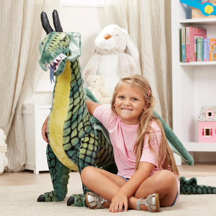 A kid playing with The Melissa & Doug Lifelike Plush Giant Winged Dragon Stuffed Animal (36 x 40.5 x 16 in)