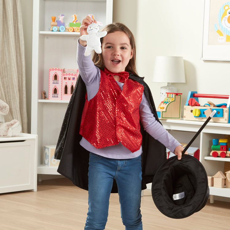 A kid playing with The Melissa & Doug Magician Costume Role Play Set - Includes Hat, Cape, Wand, Magic Tricks