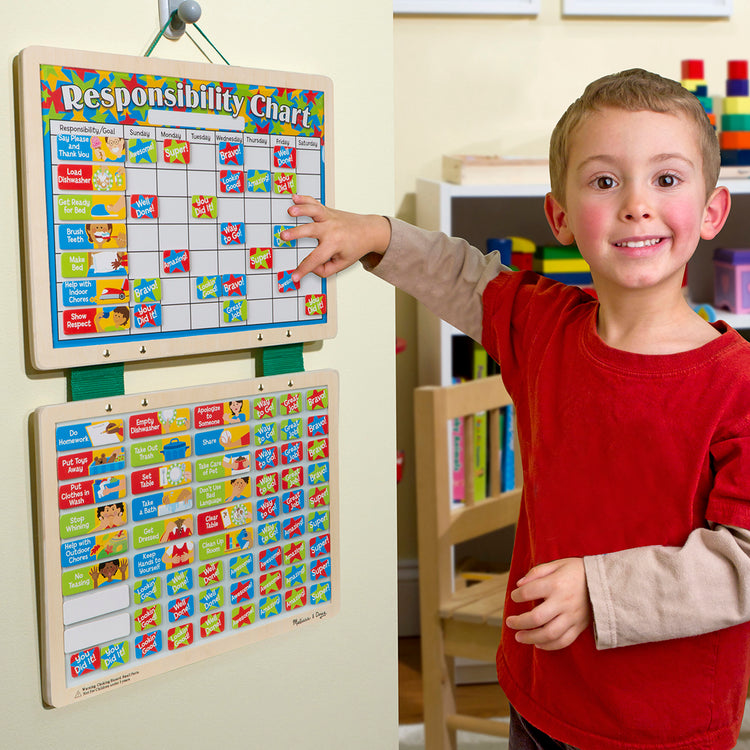 A kid playing with The Melissa & Doug Magnetic Wooden Responsibility Chart