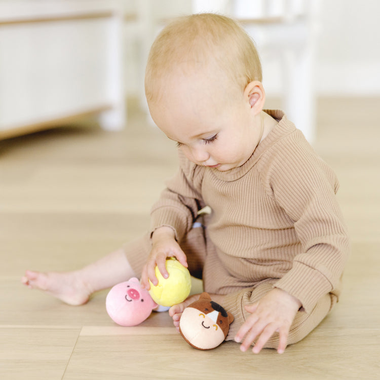 A kid playing with The Melissa & Doug Rollables Farm Friends Infant and Toddler Toy (4 Pieces)