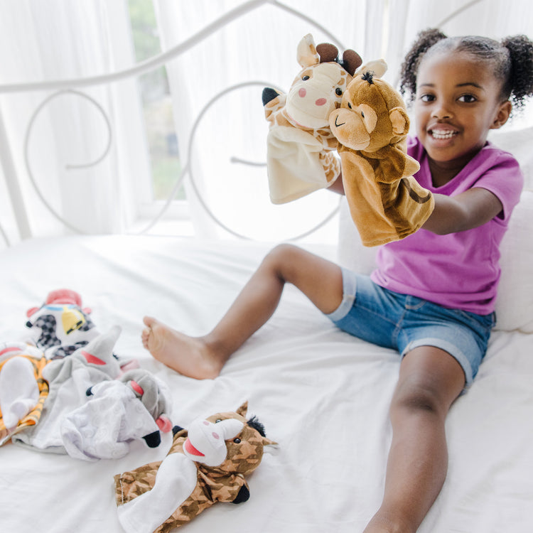 A kid playing with The Melissa & Doug Animal Hand Puppets 2-Pack (4 animals in each) - Zoo Friends and Farm Friends