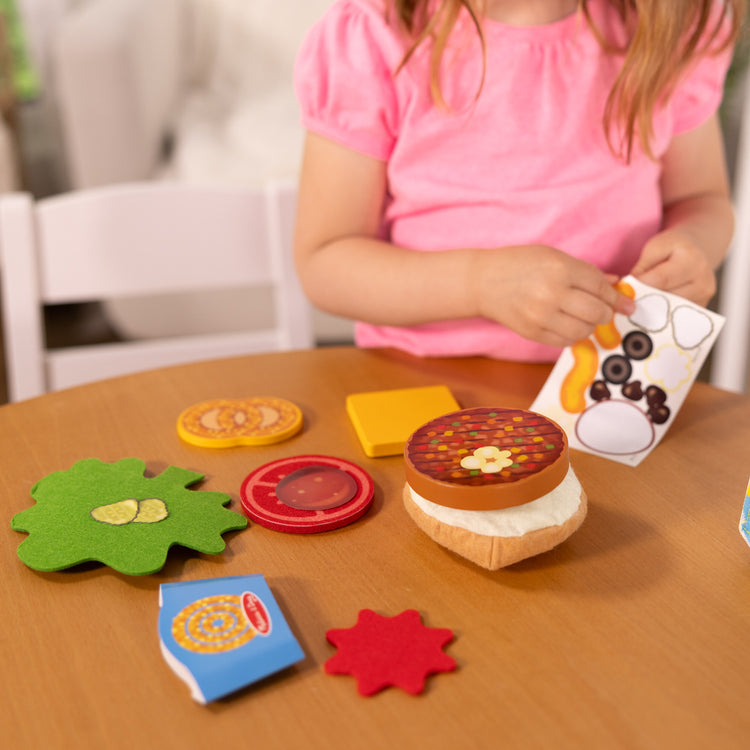 A kid playing with The Melissa & Doug What’s for Lunch?™ Surprise Meal Play Food Set Series 2