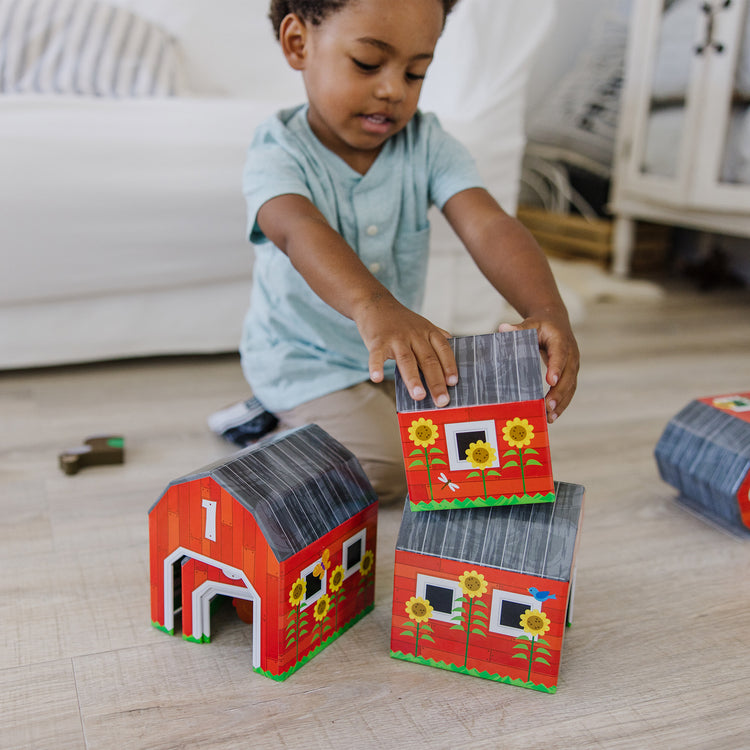 A kid playing with The Melissa & Doug Nesting and Sorting Barns and Animals With 6 Numbered Barns and Matching Wooden Animals