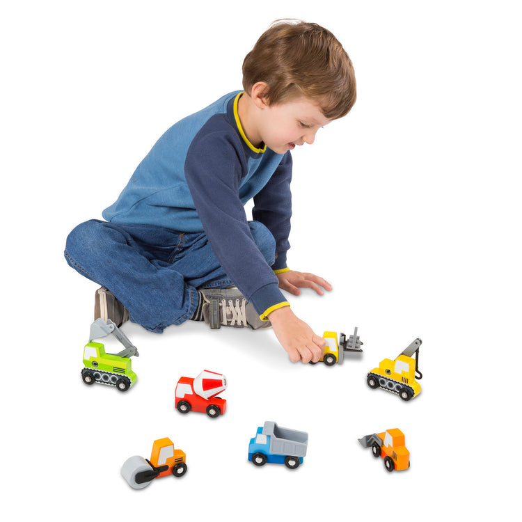A kid playing with The Melissa & Doug Wooden Construction Site Vehicles With Wooden Storage Tray (8 pcs)