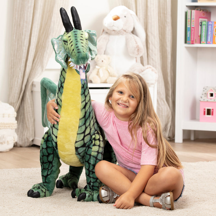 A kid playing with The Melissa & Doug Lifelike Plush Giant Winged Dragon Stuffed Animal (36 x 40.5 x 16 in)