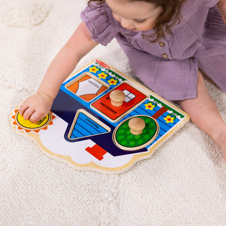 A kid playing with The Melissa & Doug First Shapes Jumbo Peg Wooden Puzzle