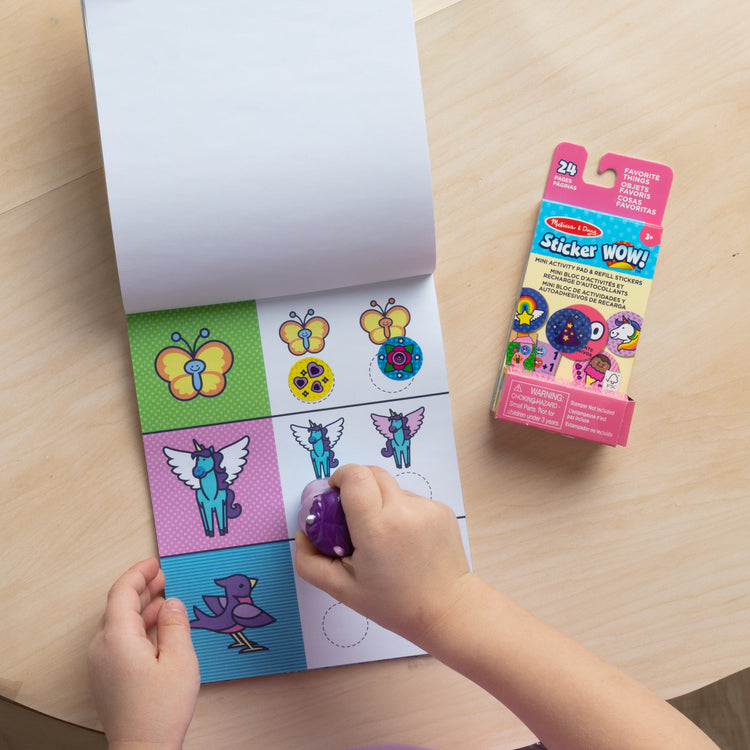 A kid playing with The Melissa & Doug Sticker WOW!™ Purple Unicorn Bundle: 24-Page Activity Pad, Sticker Stamper, 500 Stickers, Arts and Crafts Fidget Toy Collectible Character