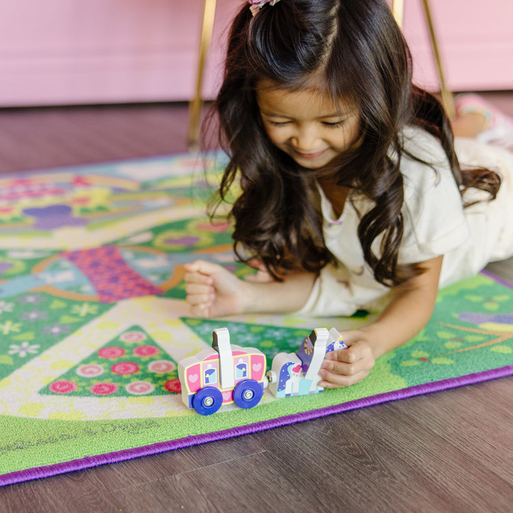 A kid playing with The Melissa & Doug Magical Kingdom Activity Rug Play Set – 4 Wooden Play Pieces