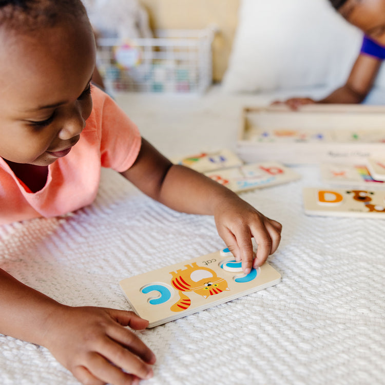 A kid playing with The Melissa & Doug ABC Picture Boards - Educational Toy With 13 Double-Sided Wooden Boards and 52 Letters