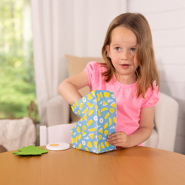 A kid playing with The Melissa & Doug What’s for Lunch?™ Surprise Meal Play Food Set Series 2