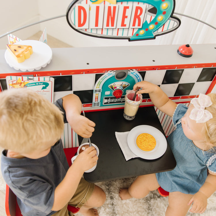 A kid playing with The Melissa & Doug Double-Sided Wooden Star Diner Restaurant Play Space