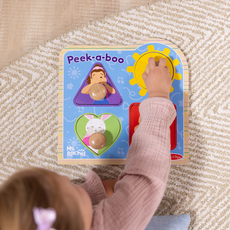 A kid playing with The Melissa & Doug® Ms. Rachel™ Wooden Peek-a-Boo Jumbo Peg Puzzle, 4-Piece with Mirror, Toddler Toys for Boys and Girls Ages 1+ Years

