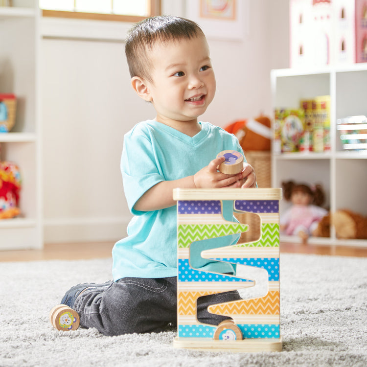 A kid playing with The Melissa & Doug First Play Wooden Safari Zig-Zag Tower With 4 Rolling Pieces