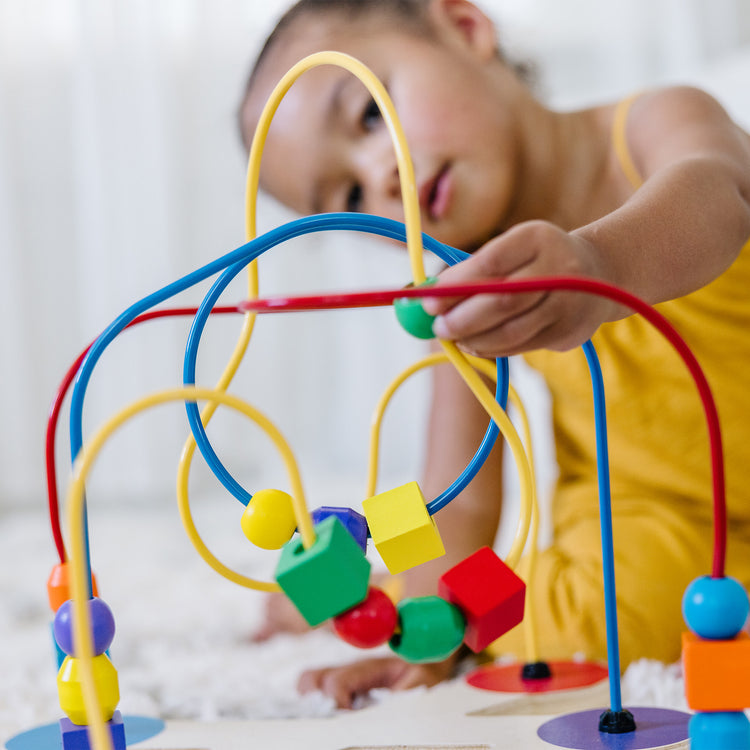 A kid playing with The Melissa & Doug Classic Bead Maze - Wooden Educational Toy