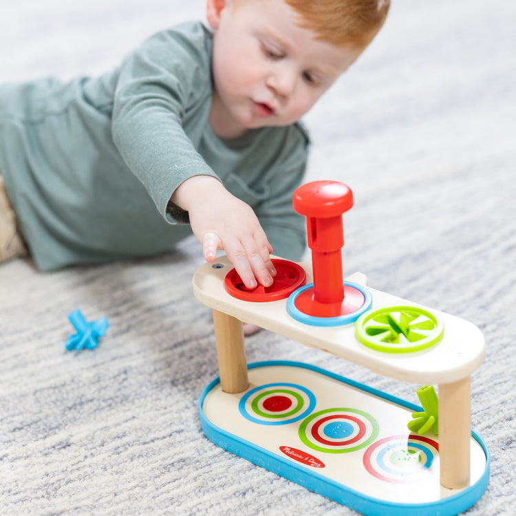 A kid playing with The Melissa & Doug Match & Push Spinning Tops Developmental Skills Toy for Girls and Boys 2+ 