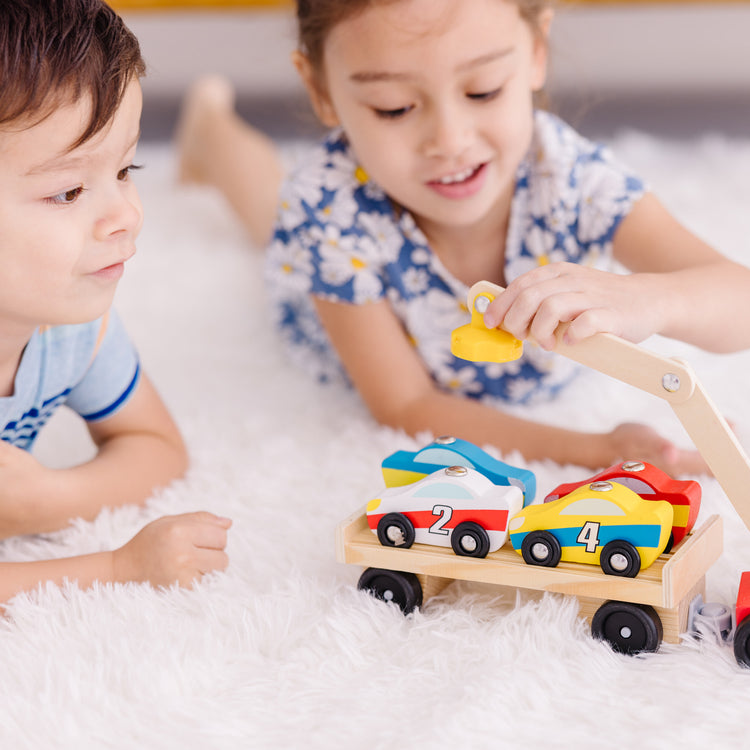 A kid playing with The Melissa & Doug Magnetic Car Loader Wooden Toy Set With 4 Cars and 1 Semi-Trailer Truck