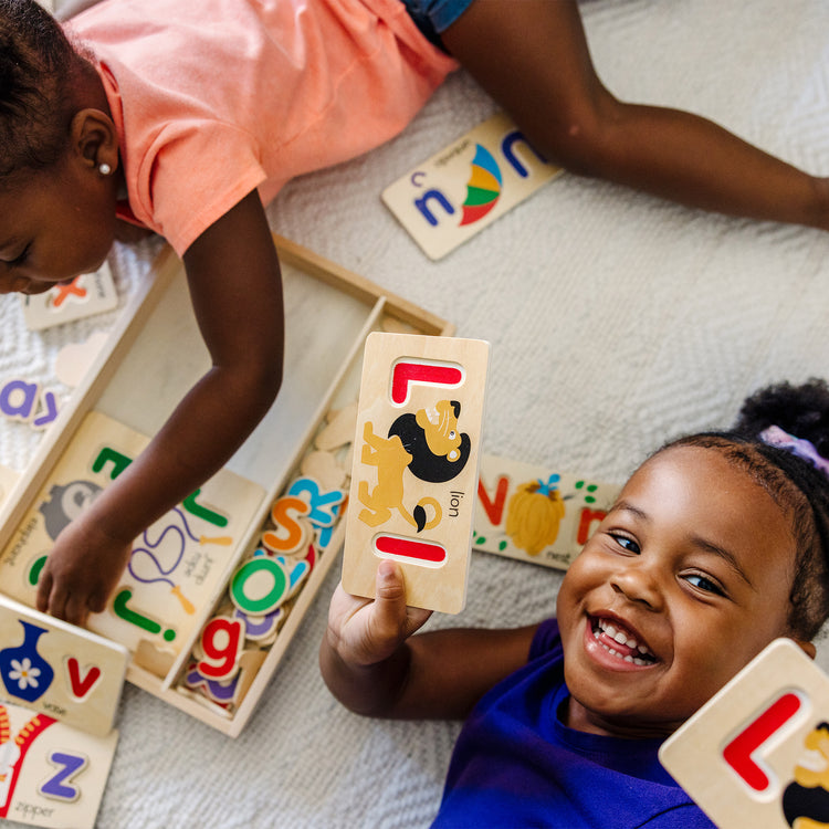 A kid playing with The Melissa & Doug ABC Picture Boards - Educational Toy With 13 Double-Sided Wooden Boards and 52 Letters