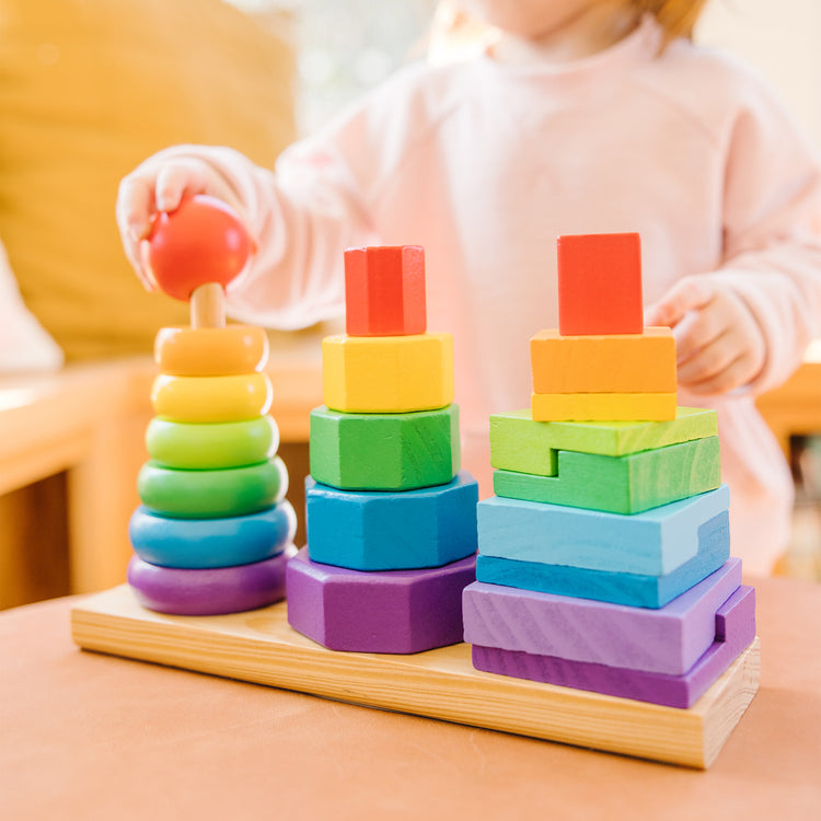 A kid playing with The Melissa & Doug Geometric Stacker - Wooden Educational Toy