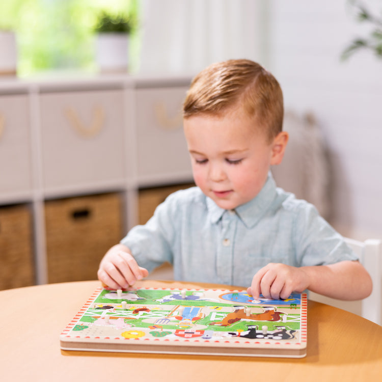 A kid playing with The Melissa & Doug Old MacDonald's Farm Sound Puzzle With Light-Activated Sound Effects