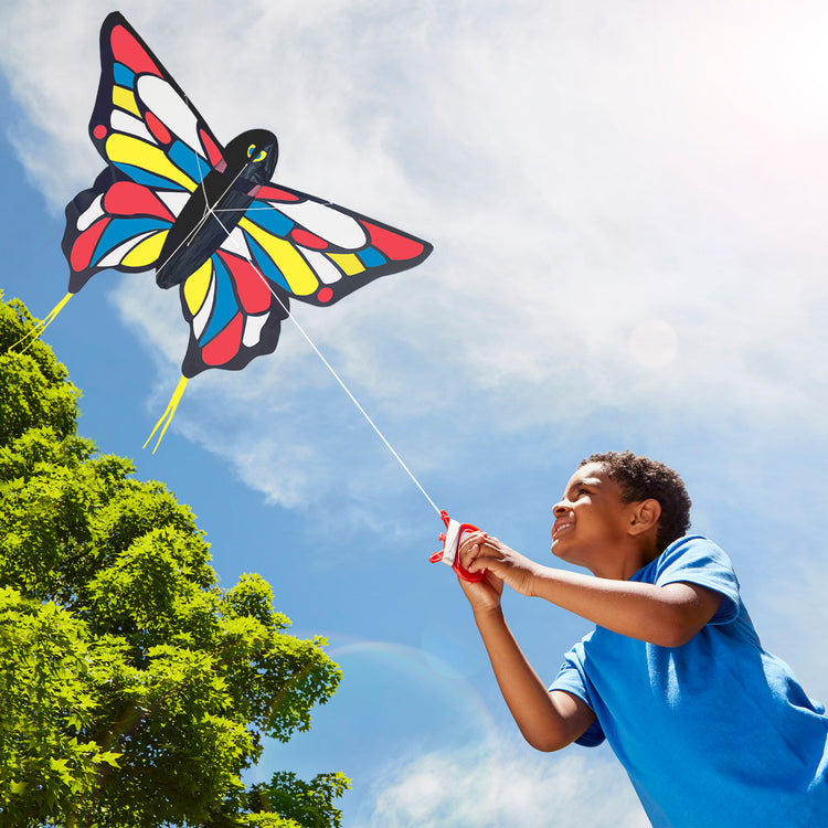 A kid playing with The Melissa & Doug Beautiful Butterfly Single Line Shaped Kite (50-Inch Wingspan)