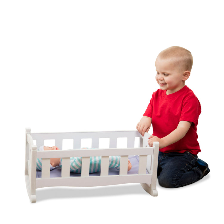 A child on white background with The Melissa & Doug Mine to Love Wooden Play Cradle for Dolls, Stuffed Animals - White