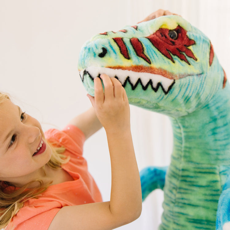 A kid playing with The Melissa & Doug Standing T-Rex Giant Lifelike Plush Stuffed Animal