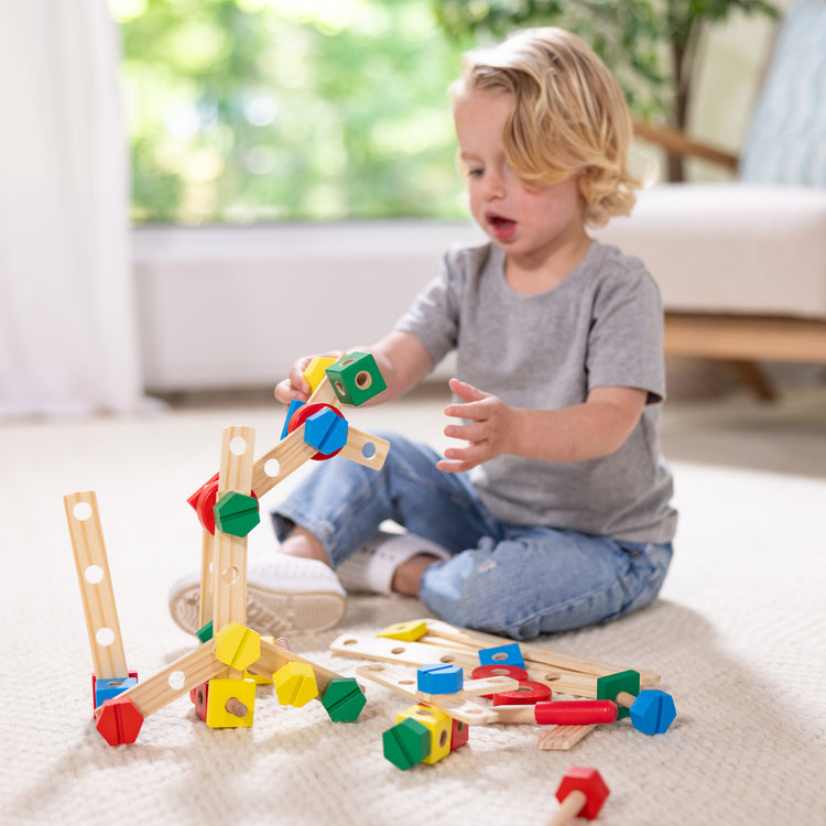 A kid playing with The Melissa & Doug Wooden Construction Building Toy Play Set in a Box, Developmental Educational Toy (48 pcs)