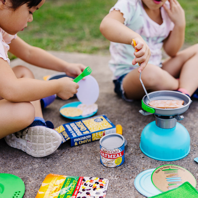 A kid playing with The Melissa & Doug Let’s Explore Outdoor Cooking Play Set – 27 Pieces