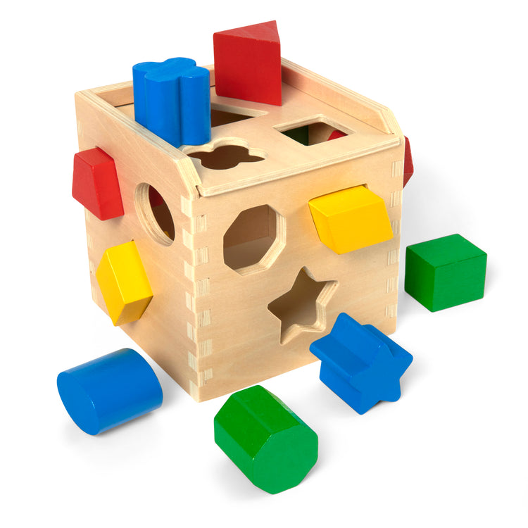 A kid playing with The Melissa & Doug Shape Sorting Cube - Classic Wooden Toy With 12 Shapes