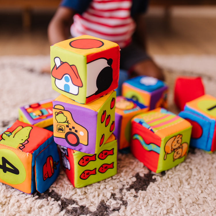 A kid playing with The Melissa & Doug K's Kids Match and Build Soft Blocks Set