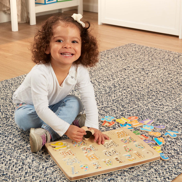 A kid playing with The Melissa & Doug Numbers Sound Puzzle - Wooden Counting Puzzle With Sound Effects (21 pcs)