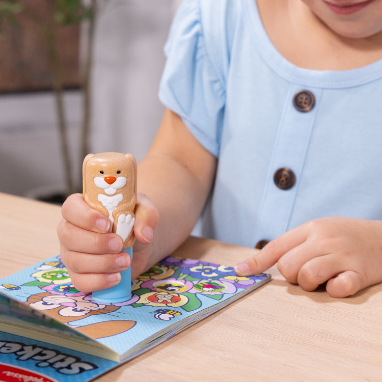 A kid playing with The Melissa & Doug Sticker WOW!™ Bunny Bundle: 24-Page Activity Pad, Sticker Stamper, 500 Stickers, Mini Pad, Arts and Crafts Fidget Toy Collectible Character