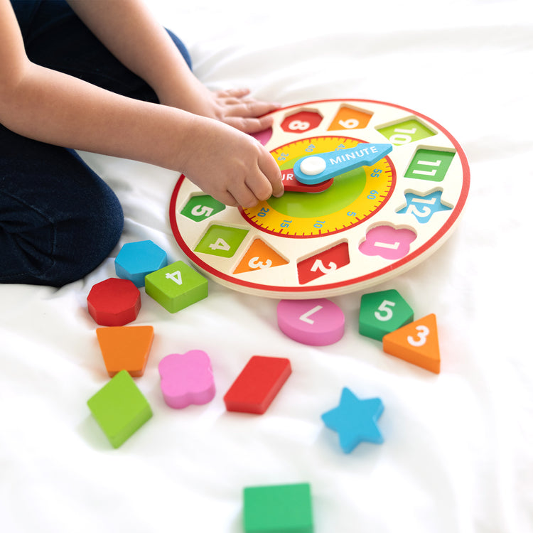 A kid playing with The Melissa & Doug Shape Sorting Clock - Wooden Educational Toy