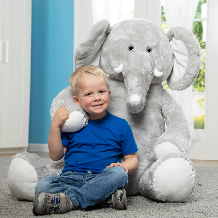 A kid playing with The Melissa & Doug Gentle Jumbos Elephant Giant Stuffed Plush Animal (Sits Nearly 3 Feet Tall)