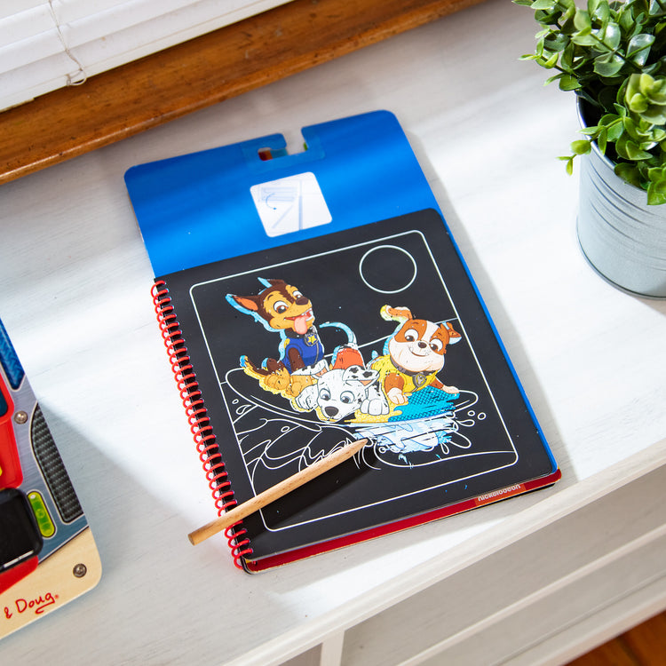 A playroom scene with The Melissa & Doug PAW Patrol Scratch Art Pad - Chase Color Reveal Travel Activity Pad (10 Scenes)