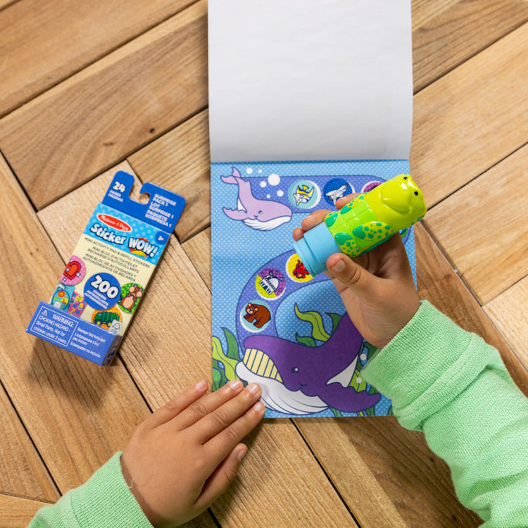 A kid playing with The Melissa & Doug Sticker WOW!™ Sea Turtle Bundle: 24-Page Activity Pad, Sticker Stamper, 500 Stickers, Arts and Crafts Fidget Toy Collectible Character