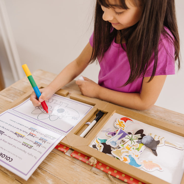 A kid playing with The Melissa & Doug Natural Play: Play, Draw, Create Dinosaurs Drawing Activity Set & Magnet Kit - Reusable Mess-Free Travel Activity